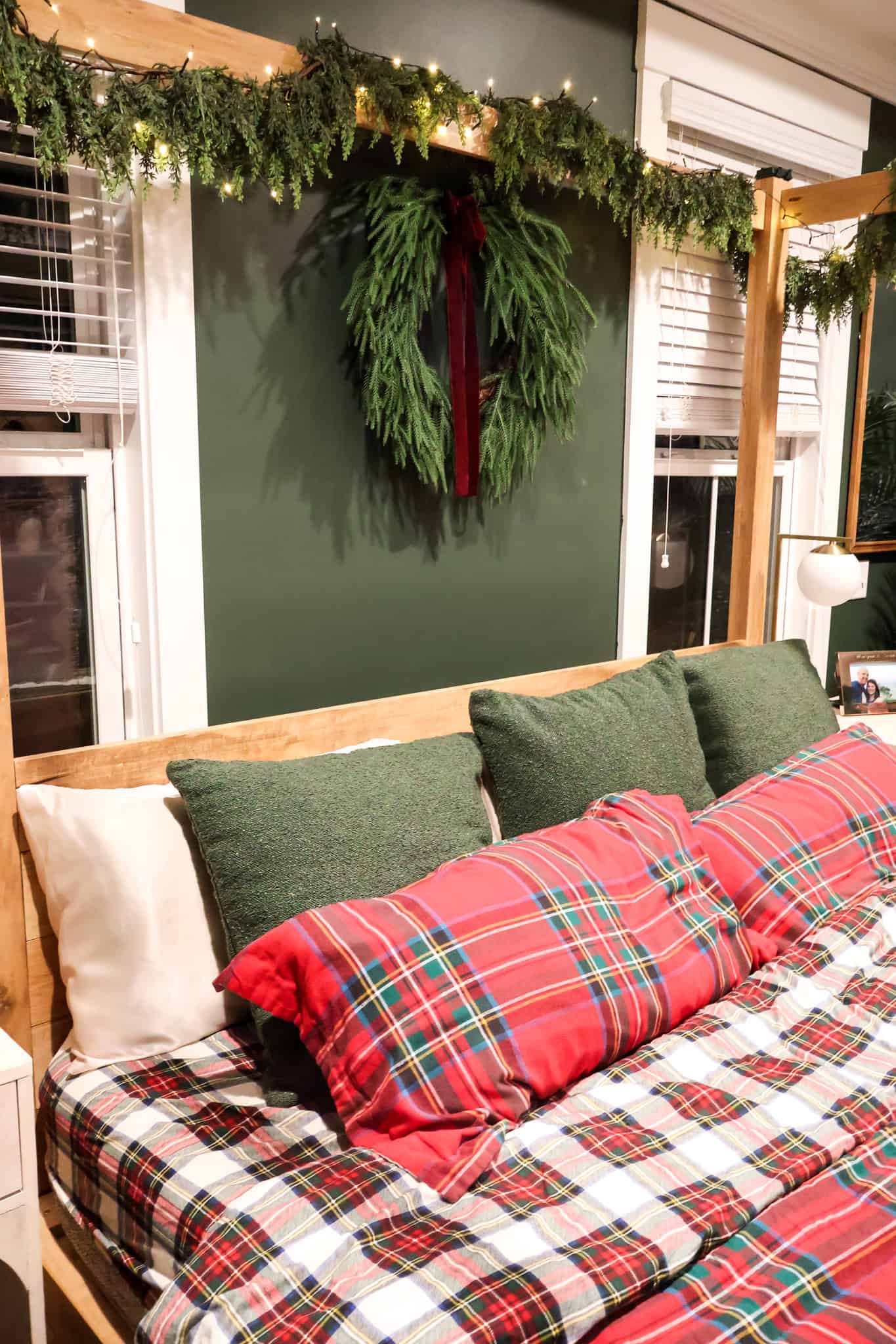 Bed As Central Focus With Garland Above Traditional Christmas Bedroom with Red Plaid Bedding and Garland Bed As Central Focus With Garland Above Traditional Christmas Bedroom with Red Plaid Bedding and Garland — Christmas Bedroom