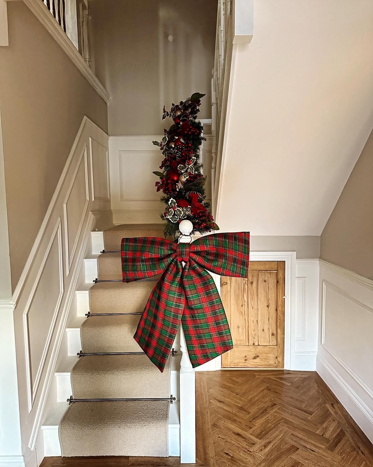 Lush Garland Topped with a Bold Tartan Bow Lush Garland Topped with a Bold Tartan Bow — Christmas Staircase Decor