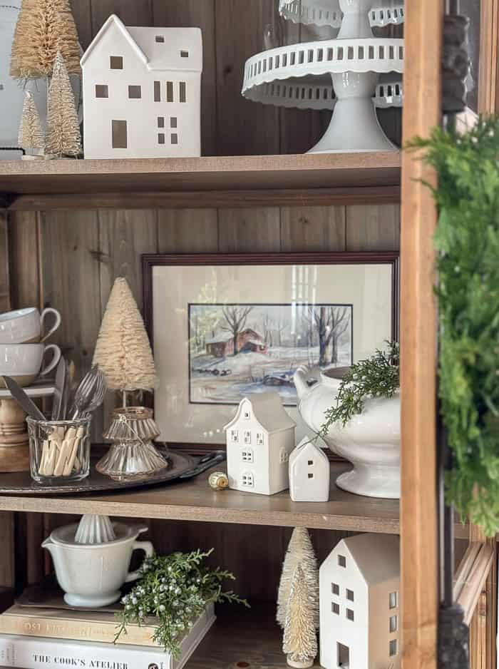 Farmhouse Kitchen Shelf with White Ceramic Houses and Trees Farmhouse Kitchen Shelf with White Ceramic Houses and Trees — Christmas Bookshelf Decor