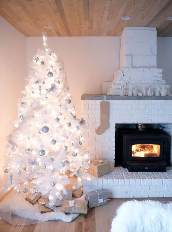 Heavily Flocked White Tree Next to a White Brick Fireplace Heavily Flocked White Tree Next to a White Brick Fireplace — White Christmas Tree Decor