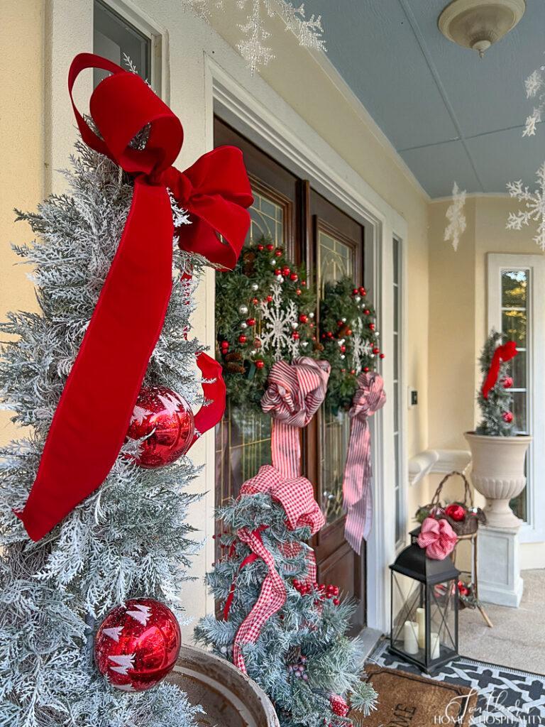 Traditional Porch with Flocked Trees and Red Velvet Bows Traditional Porch with Flocked Trees and Red Velvet Bows — Christmas Front Door Decor