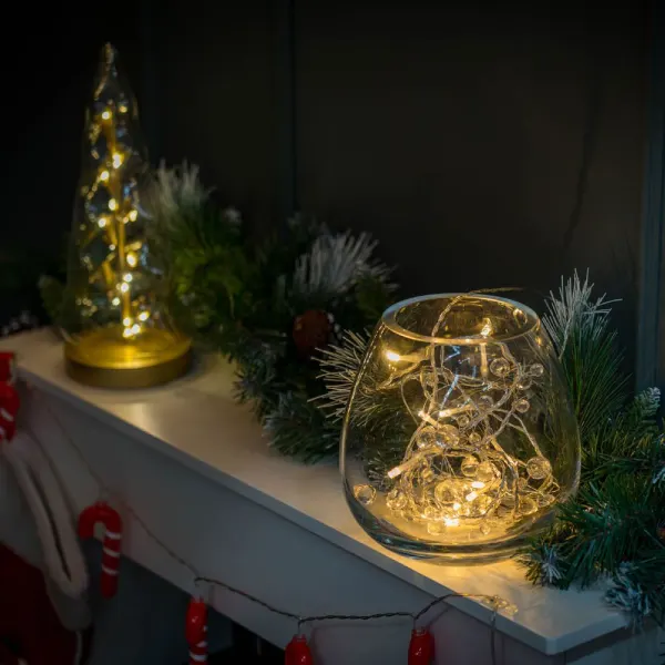String Lights Illuminate Glass Vessels and Greenery on a Mantel — Christmas Lights Indoor