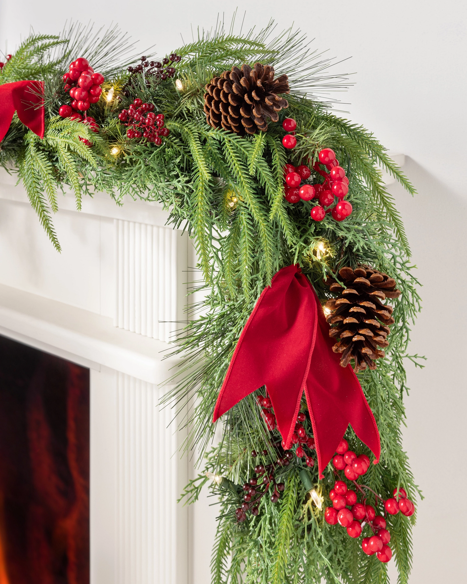 Artificial Garland with Large Red Velvet Bows on a White Mantel Artificial Garland with Large Red Velvet Bows on a White Mantel — Christmas Garland
