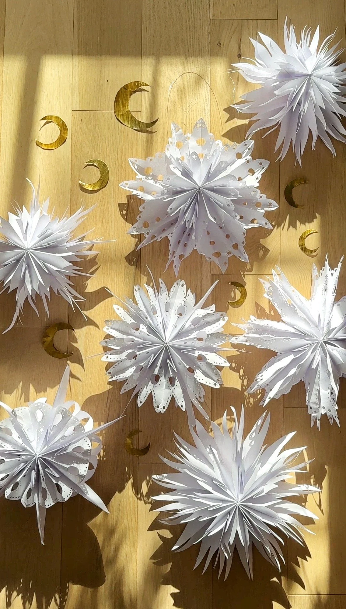 Whimsical 3D Paper Snowflakes on a Light Wood Floor