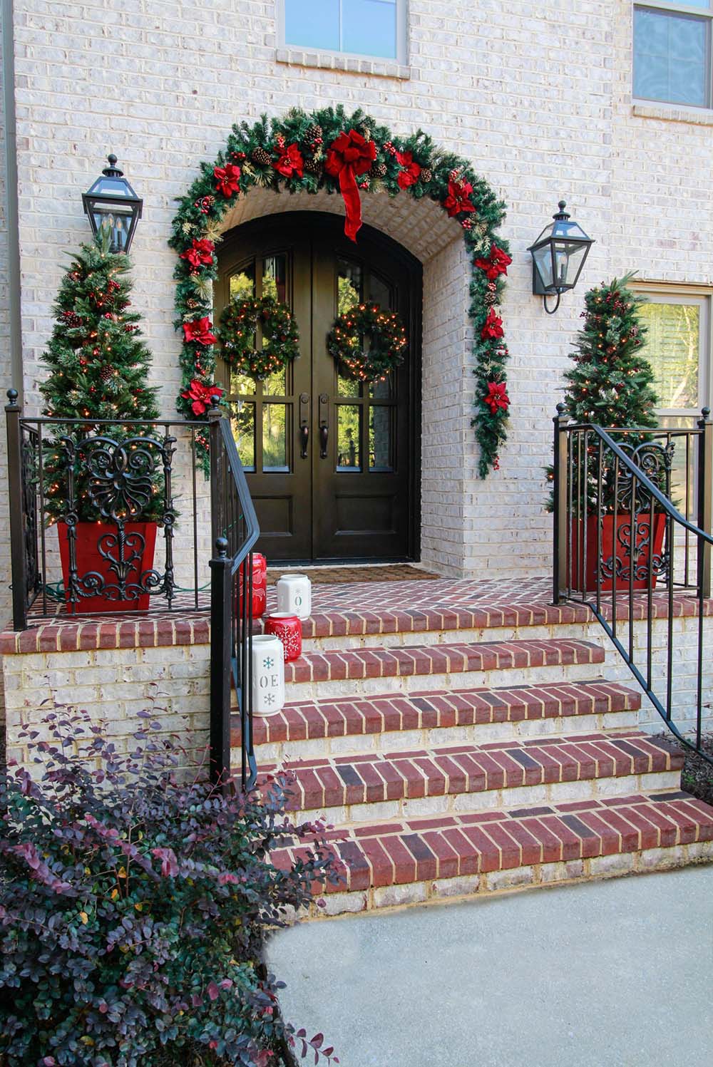Grand Double Doors with Lush Garland Arch and Red Flowers Grand Double Doors with Lush Garland Arch and Red Flowers — Christmas Front Door Decor