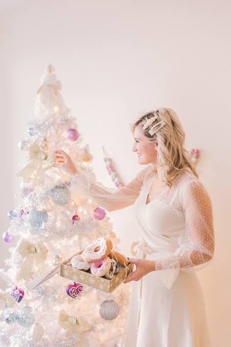 Woman Decorating a White Christmas Tree with Donuts Woman Decorating a White Christmas Tree with Donuts — White Christmas Tree Decor