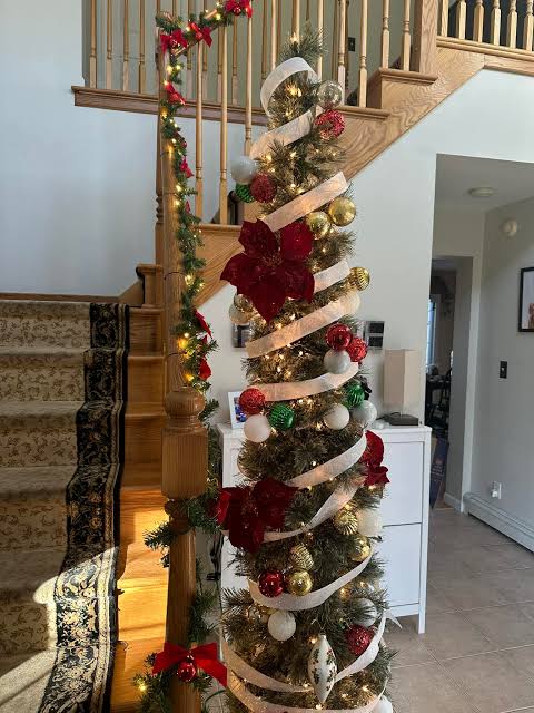Slim Tree by a Staircase with Gold Ribbon and Red Flowers — Slim Christmas Tree Decor