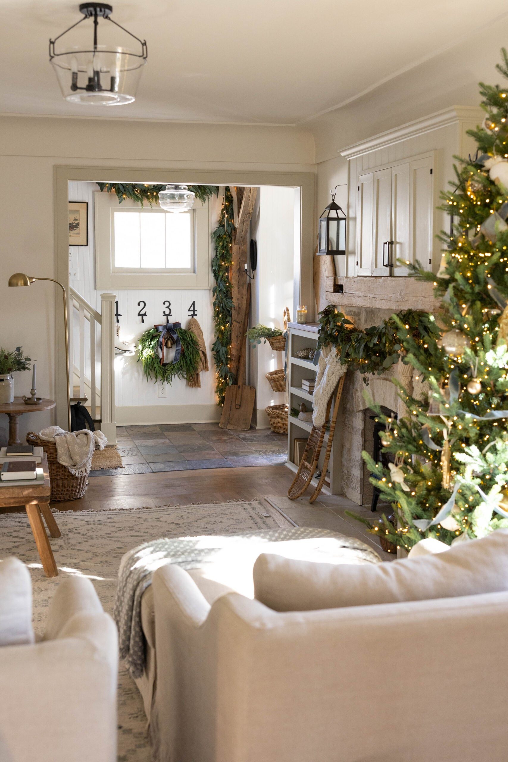 Rustic Living Room with a Stone Fireplace Draped in Garland and Twinkling Lights — Christmas Living Room Decor