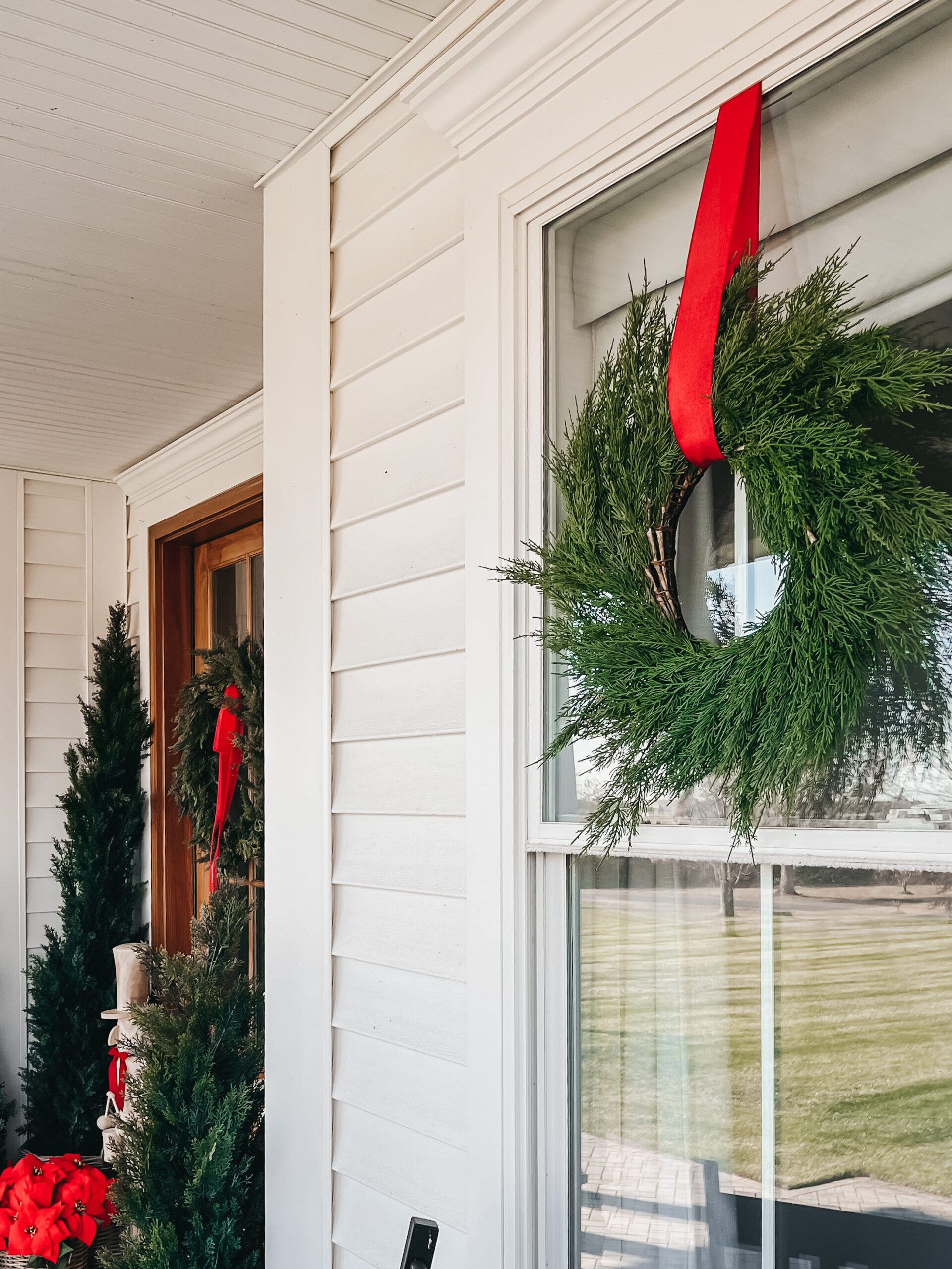 Farmhouse Wreath with Vibrant Red Ribbon on White Trim — Christmas Window Wreaths