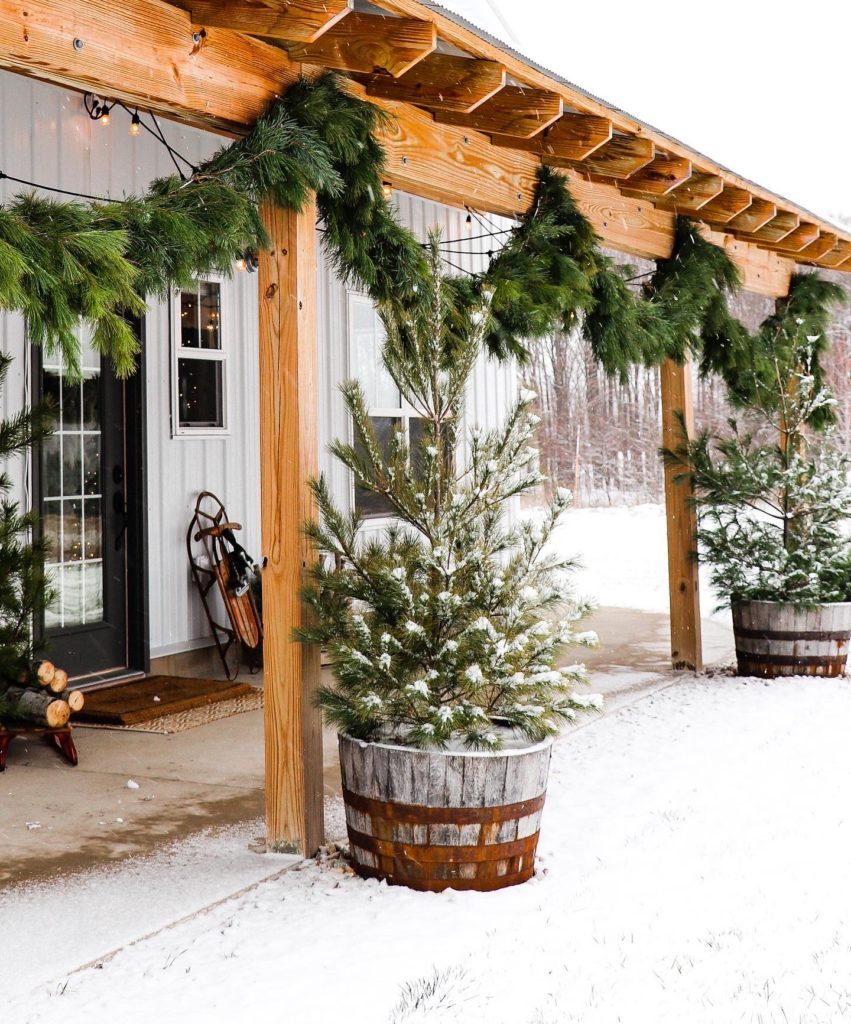 Farmhouse Porch with Pine Garland and Potted Christmas Trees Farmhouse Porch with Pine Garland and Potted Christmas Trees — Christmas Yard Decor