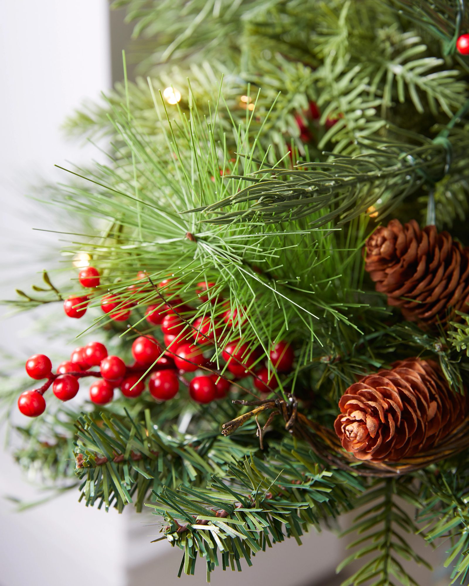 Close-up of Artificial Christmas Tree Branches with Red Berries — Red and Green Christmas Decor