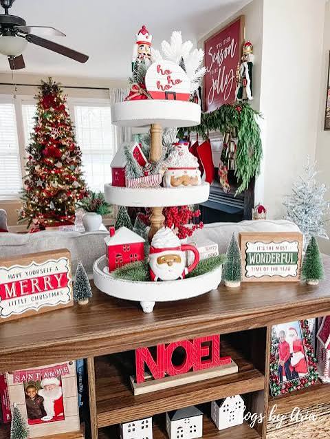 Living Room White Tiered Tray Overflowing with Santa Figures and Mini Houses — Christmas Tiered Tray