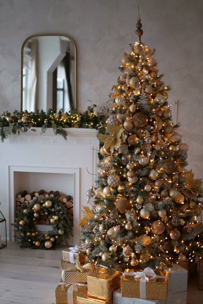Elegant traditional Christmas tree with gold and white ornaments near a fireplace Elegant traditional Christmas tree with gold and white ornaments near a fireplace — Gold and White Christmas Tree