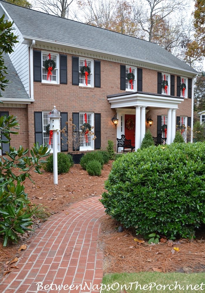 Symmetrical Wreaths on Brick House Windows for Traditional Charm — Christmas Window Wreaths