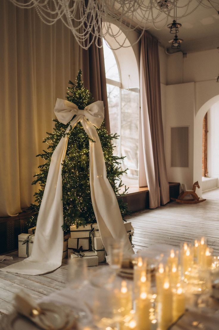 Minimalist Tree with a Dramatic Oversized White Fabric Bow Minimalist Tree with a Dramatic Oversized White Fabric Bow — Christmas Tree Trends 2026