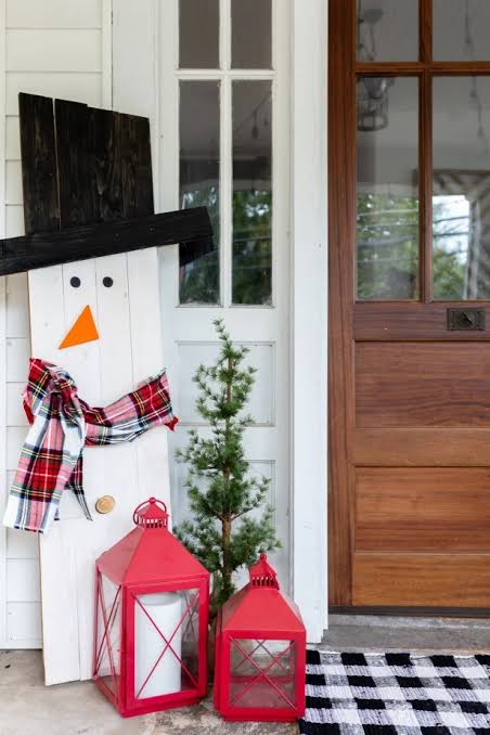 Rustic Wooden Snowman Decoration Beside a Wooden Door Rustic Wooden Snowman Decoration Beside a Wooden Door — Christmas Front Door Decor