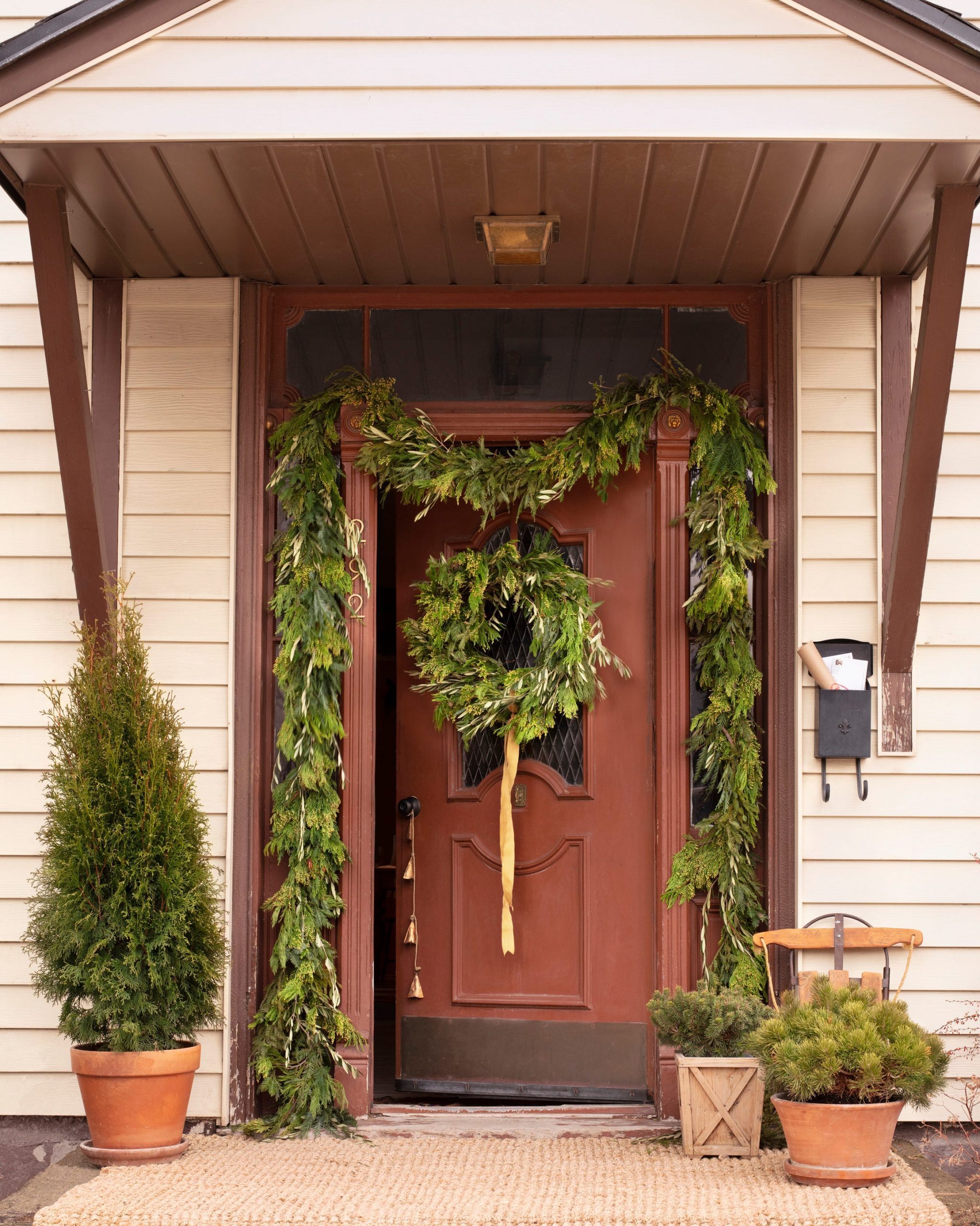 Red Front Door with Lush Garland and Rustic Bells Red Front Door with Lush Garland and Rustic Bells — Christmas Front Door Decor