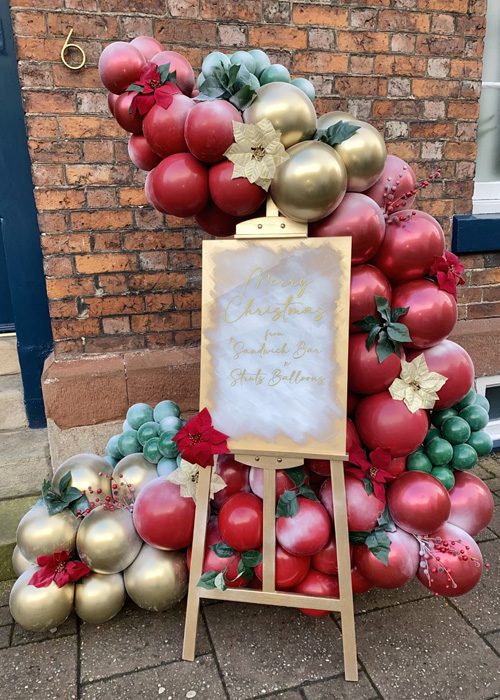 Festive Outdoor Garland Around a Wooden Easel with Poinsettias — Christmas Balloon Garland
