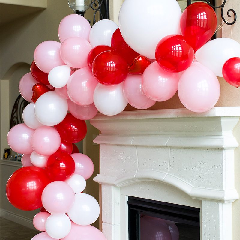 Pink, Red, and White Balloon Garland Over a Stone Fireplace — Christmas Balloon Garland