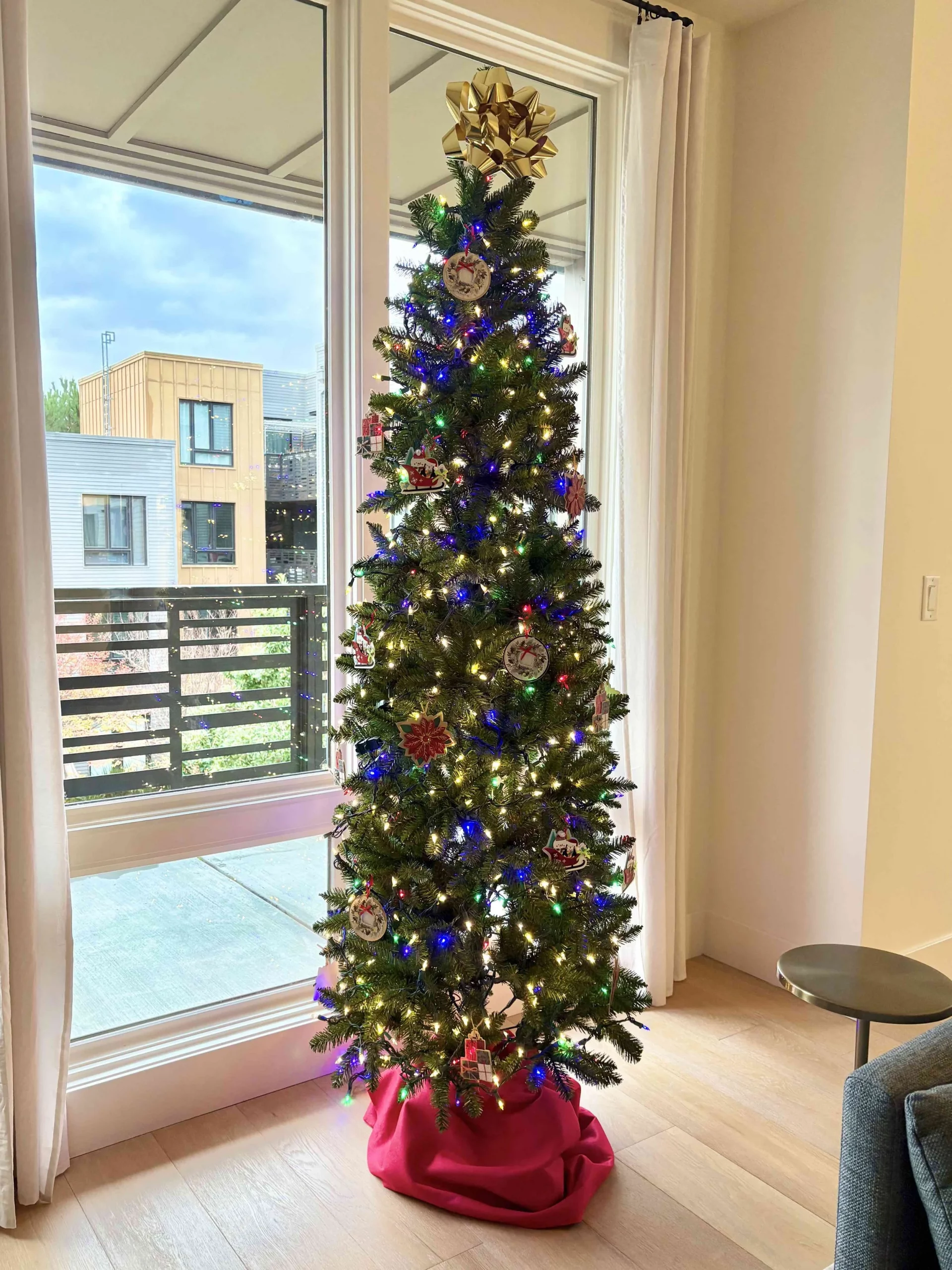 Tall Slender Tree with Multi-Colored Lights by Large Window — Minimalist Christmas Tree