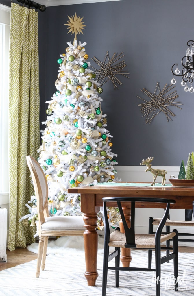 White flocked Christmas tree with gold and green ornaments in a dining room White flocked Christmas tree with gold and green ornaments in a dining room — Gold and White Christmas Tree