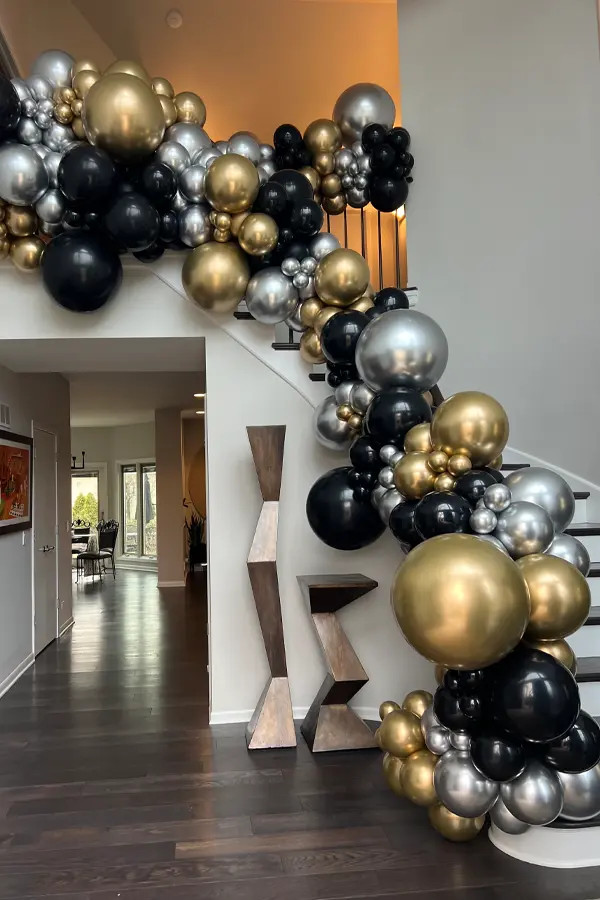Dramatic Black, Gold, and Silver Balloon Garland Cascading Down a Staircase Dramatic Black, Gold, and Silver Balloon Garland Cascading Down a Staircase — New Years Eve Balloon Garland