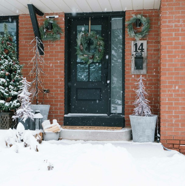 Modern Snowy Entrance with Layered Greenery and Wicker Baskets Modern Snowy Entrance with Layered Greenery and Wicker Baskets — Winter Front Door Decor