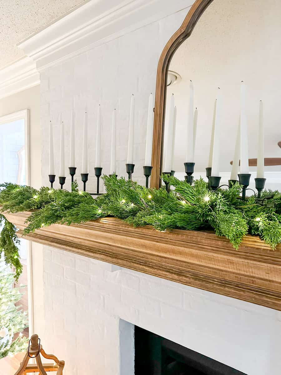 Living Room Warm Glow with Garland and Taper Candles on a Modern Farmhouse Mantel — Winter Mantel Decor
